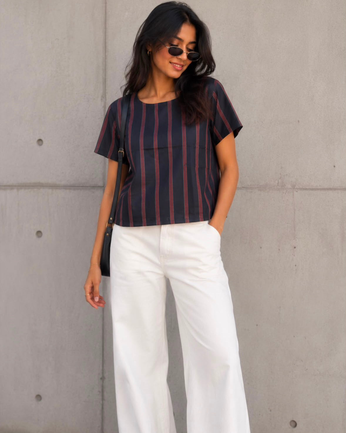 A woman wearing a black and red striped boat neck silk top.