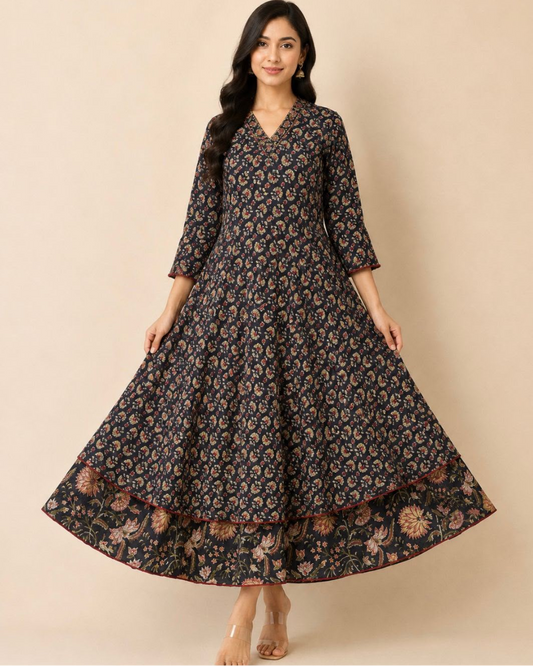 A woman modeling a long-sleeved, V-neck maxi dress with a dark navy blue base and an all-over beige and brown floral print, set against a solid beige studio background.