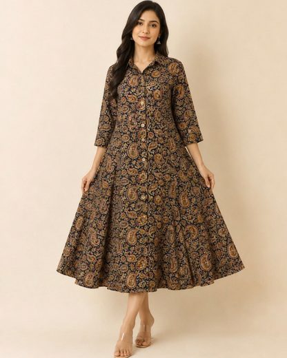 A woman modeling a long-sleeved, button-front midi dress with a flared skirt. The dress features an all-over intricate paisley and floral block print in brown, gold, and black.
