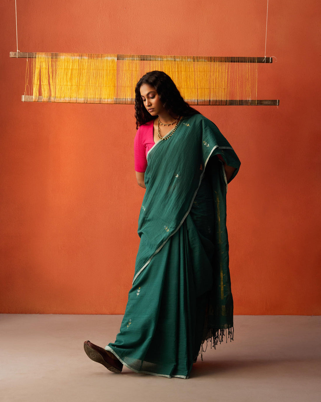 A woman wearing a dark Green saree with silver and gold jamdani