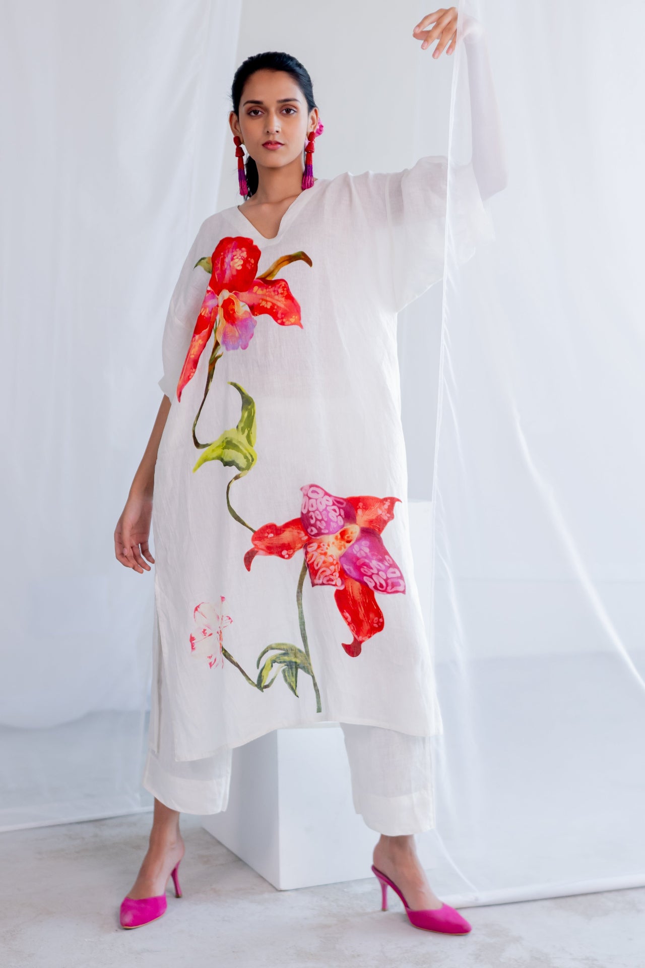 Woman wearing a white outfit with colorful floral designs against a white background

