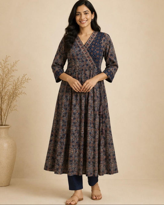 A woman modeling a dark navy blue and brown patterned cotton kurta with three-quarter sleeves, paired with navy blue pants, standing against a warm beige background.