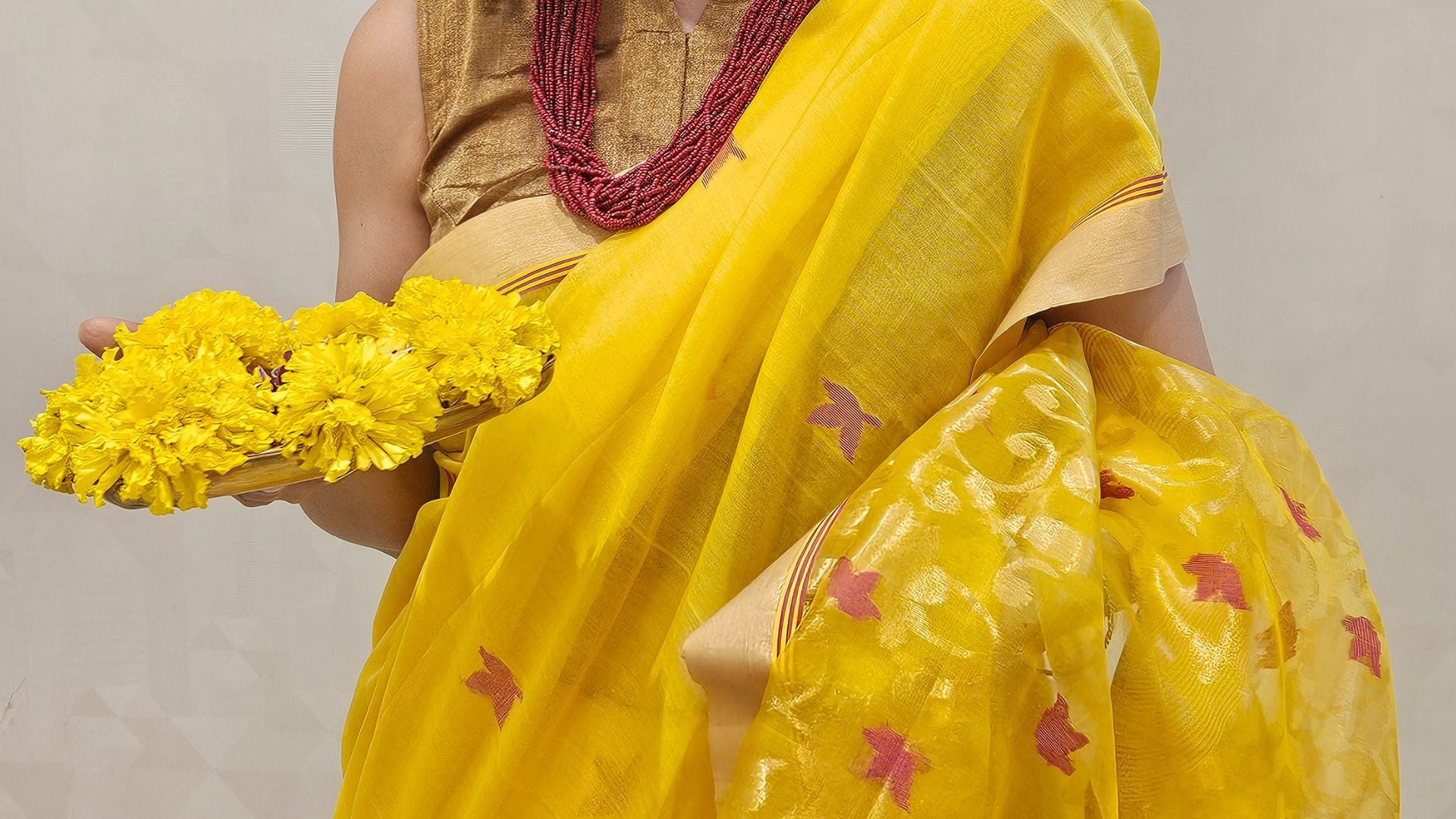 Person wearing a yellow handloom silk saree with Jamdani Red and Gold Floral Jaal